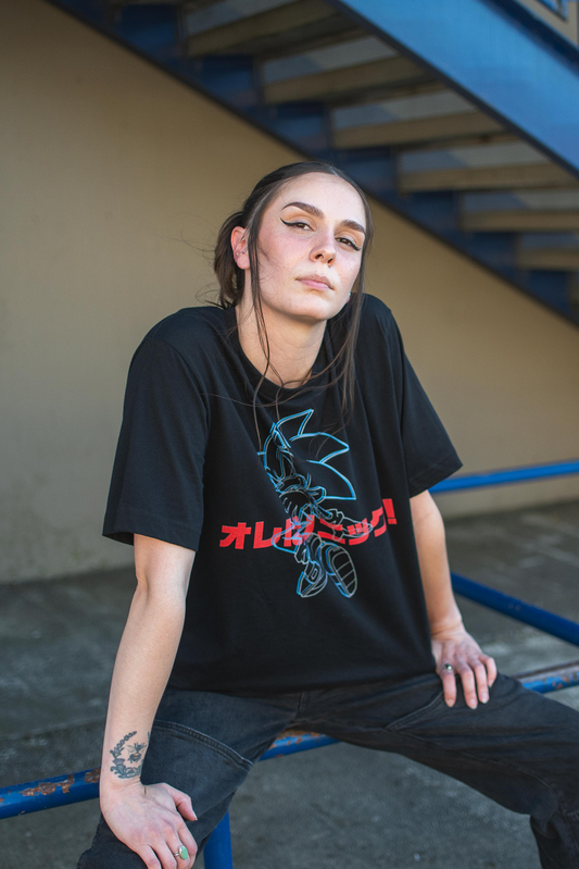 Person wearing a black t-shirt with a graphic design, sitting on a blue bench.