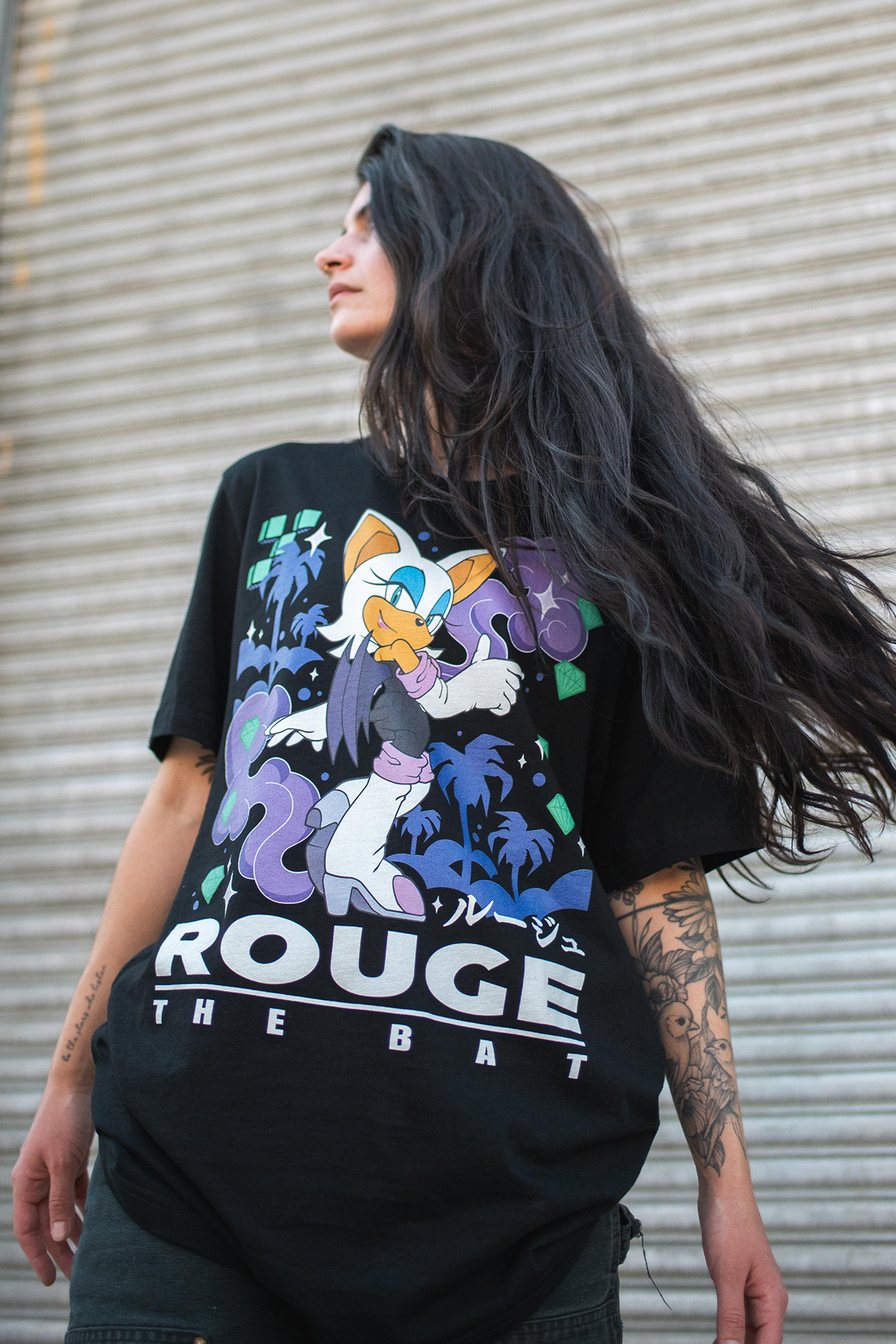 Person wearing a black t-shirt with 'Rouge the Bat' design against a metallic background